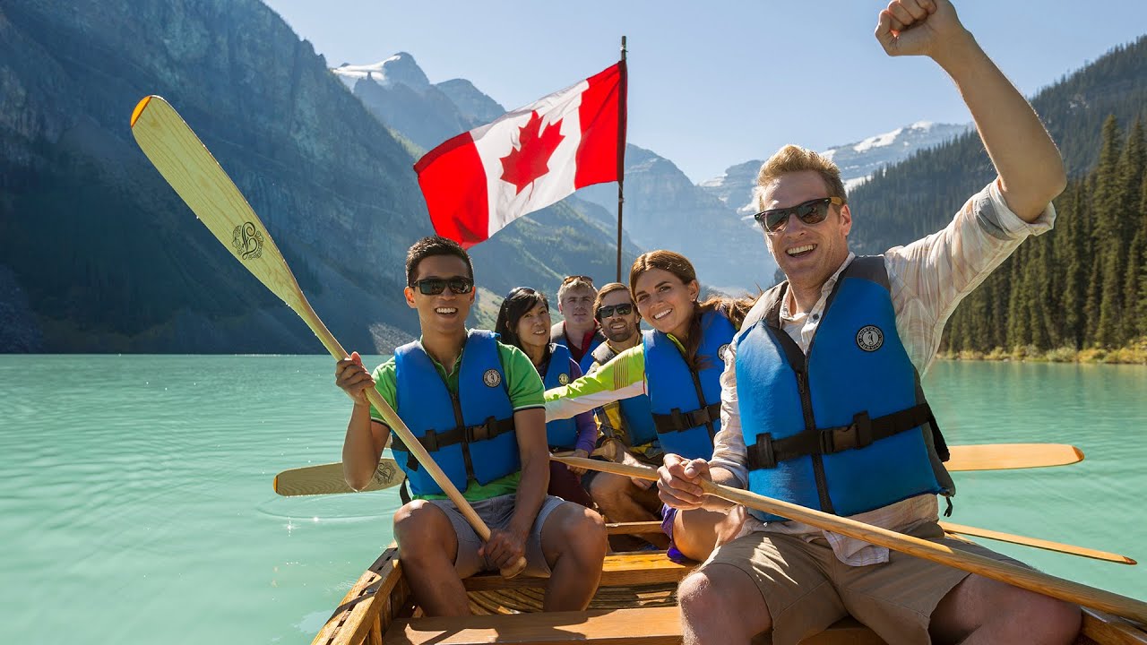 Group in voyageur canoe on Lake Louise with Canadian flag